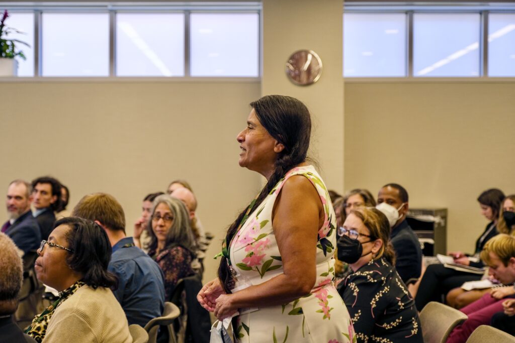 Conference participant standing in the audience to ask a question during the keynote address